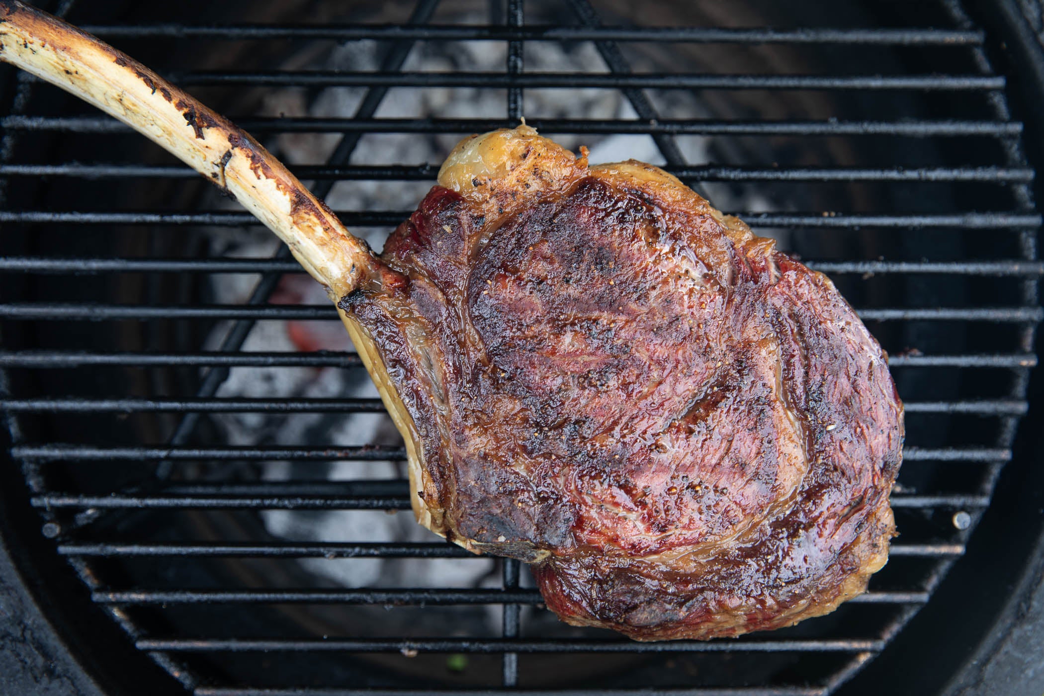 grass-fed, dry-aged tomahawk steak almost cooked on the bbq